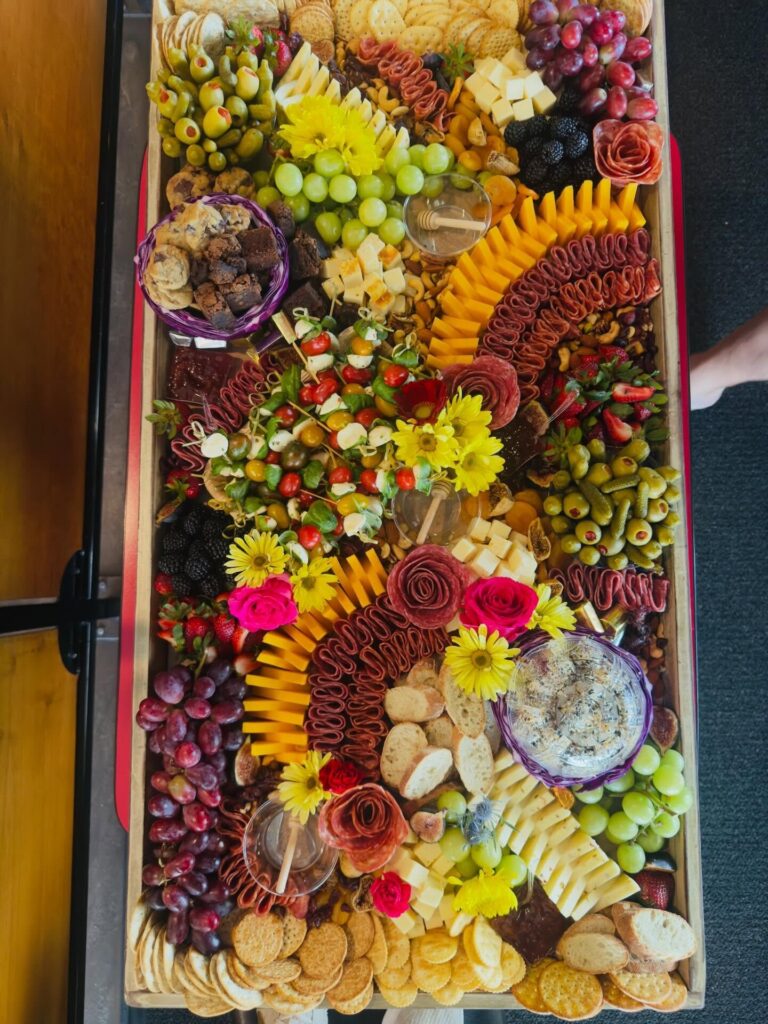 Overhead of a 3-foot board with sunflowers, salami rivers and dips