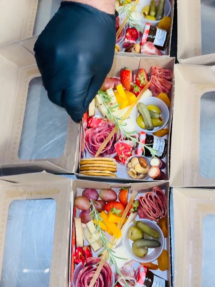 Gloved hand assembling elevated charcuterie boxes