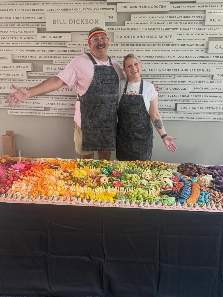 Corey and Brie presenting the rainbow grazing table at ZACH Theatre