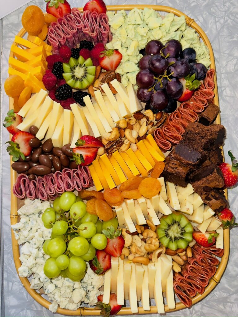 Large custom charcuterie board with grapes, cheeses, salami and dried apricots