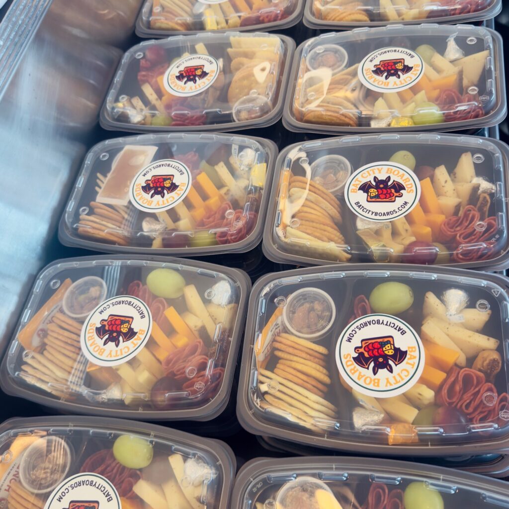 Stacked mini charcuterie boxes with branded stickers for ZACH Theatre