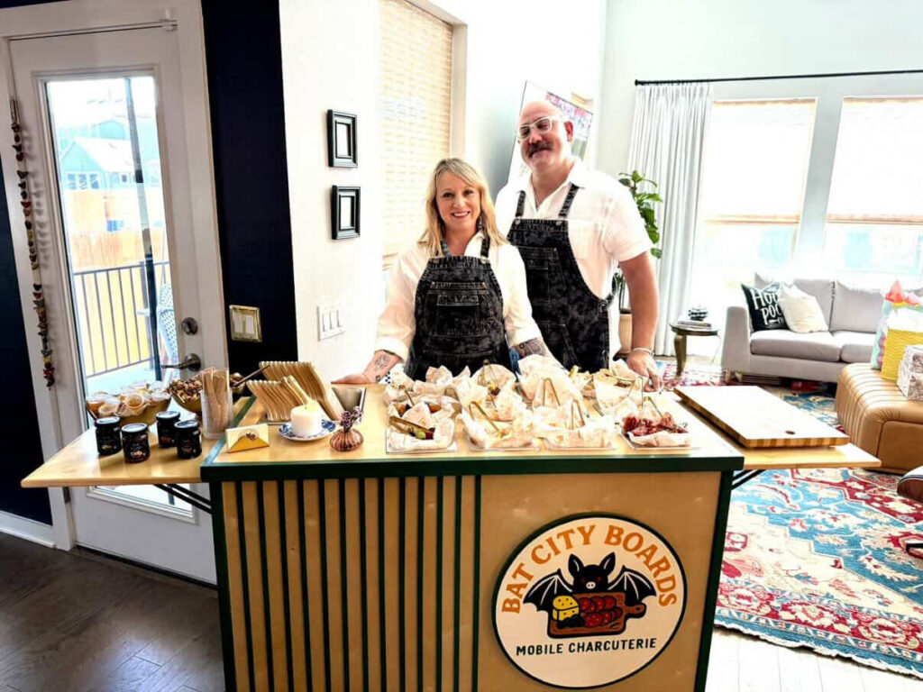 Bat City Boards founders behind the mobile charcuterie cart at a home party
