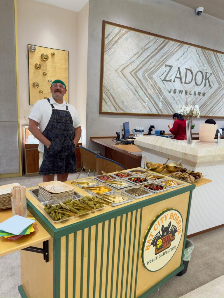 Staffed mobile charcuterie cart set up as a snack bar at a store event