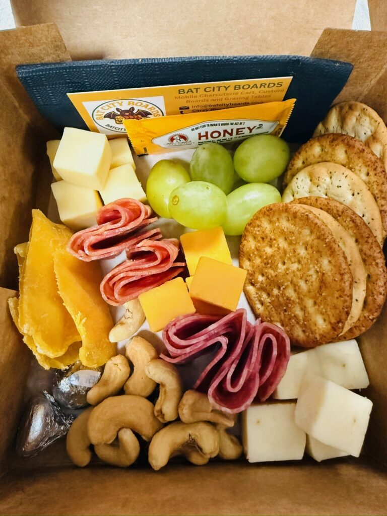 Regular charcuterie box contents: cheeses, salami, grapes, crackers and cashews