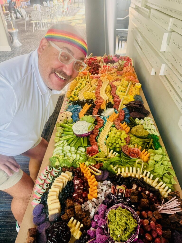 Guest posing with a rainbow-themed grazing table